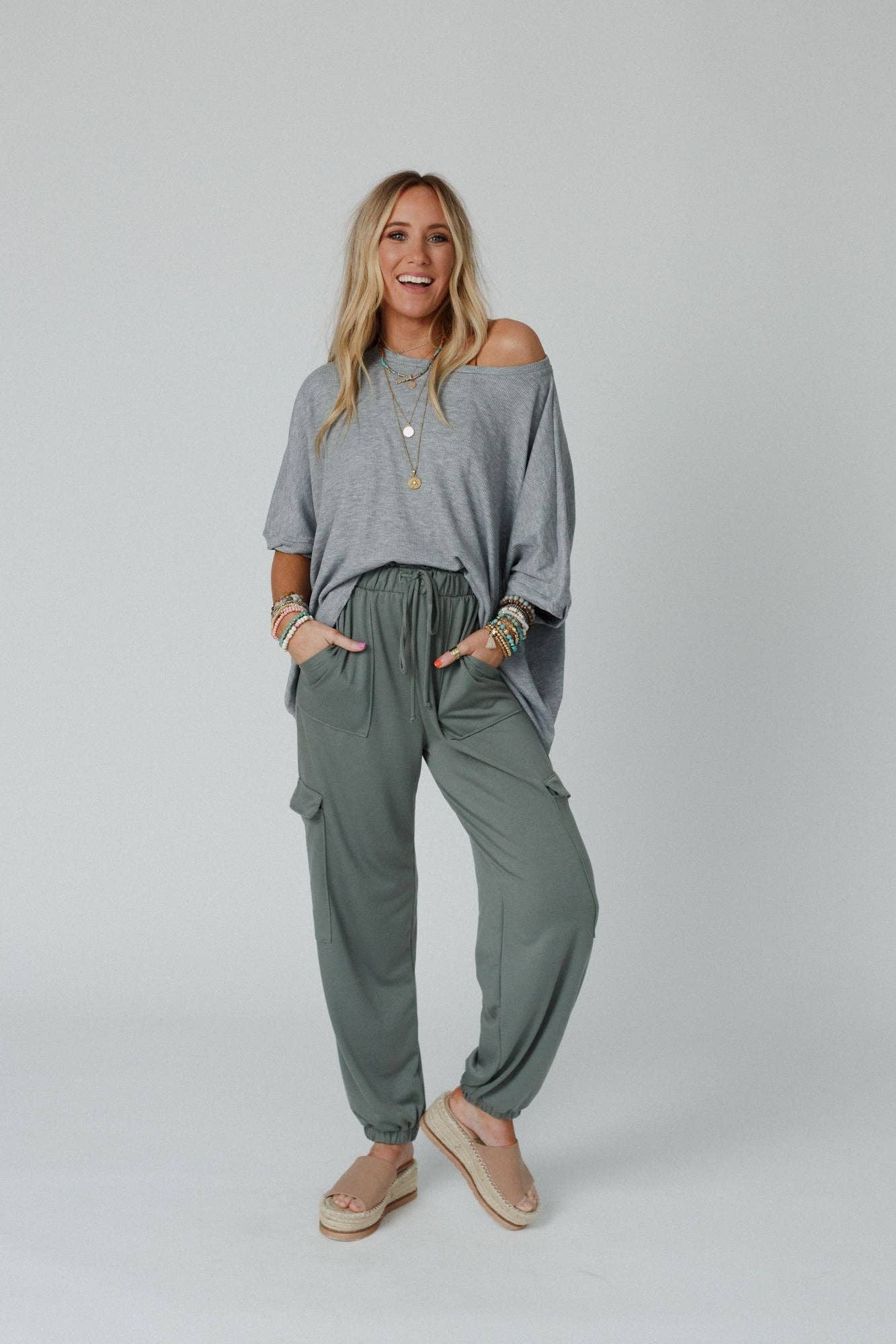 Model styled in Easy Mornings Cinched Pants by Three Bird Nest in light olive, paired with a loose gray top and platform sandals