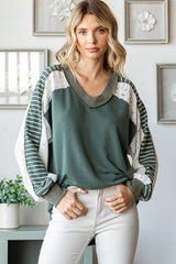 Model wearing the 7th Ray Color Block V-Neck Knit Top in a relaxed front view, highlighting the lace contrast sleeves and ribbed neckline.