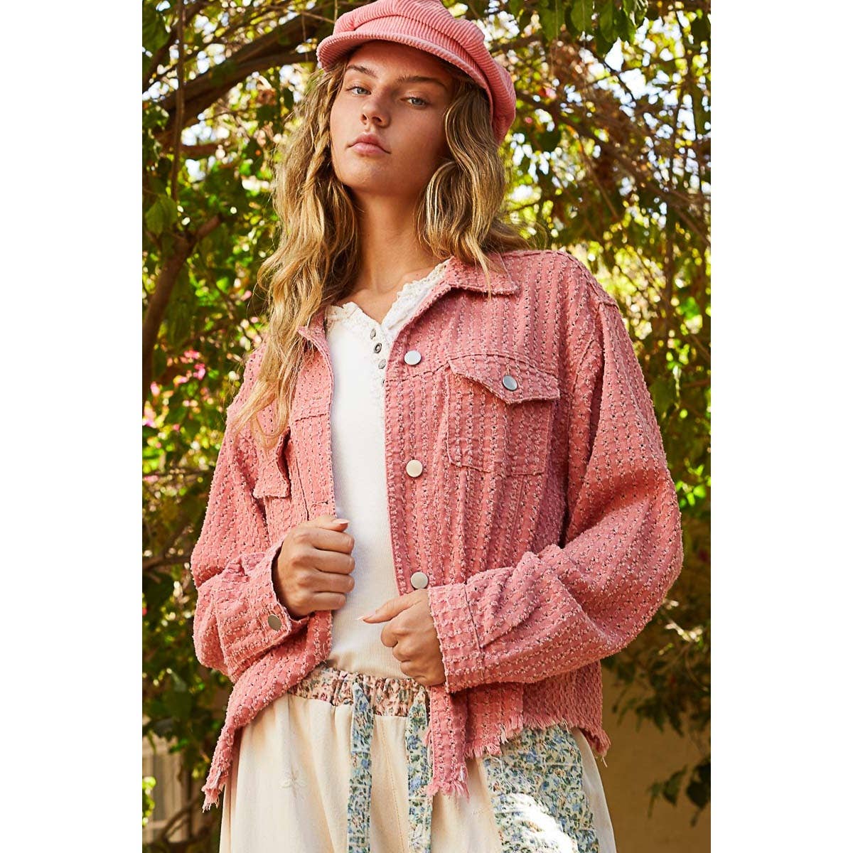 Close-up of the Pol Clothing Vintage Washed Textured Twill Jacket in a dusty pink color, featuring raw edges, front pockets, and metal buttons.