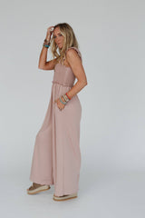 Side view of the model wearing the Three Bird Nest Nothing Compares Jumpsuit in dusty rose, highlighting the relaxed wide-leg cut and smocked bodice, paired with boho accessories.