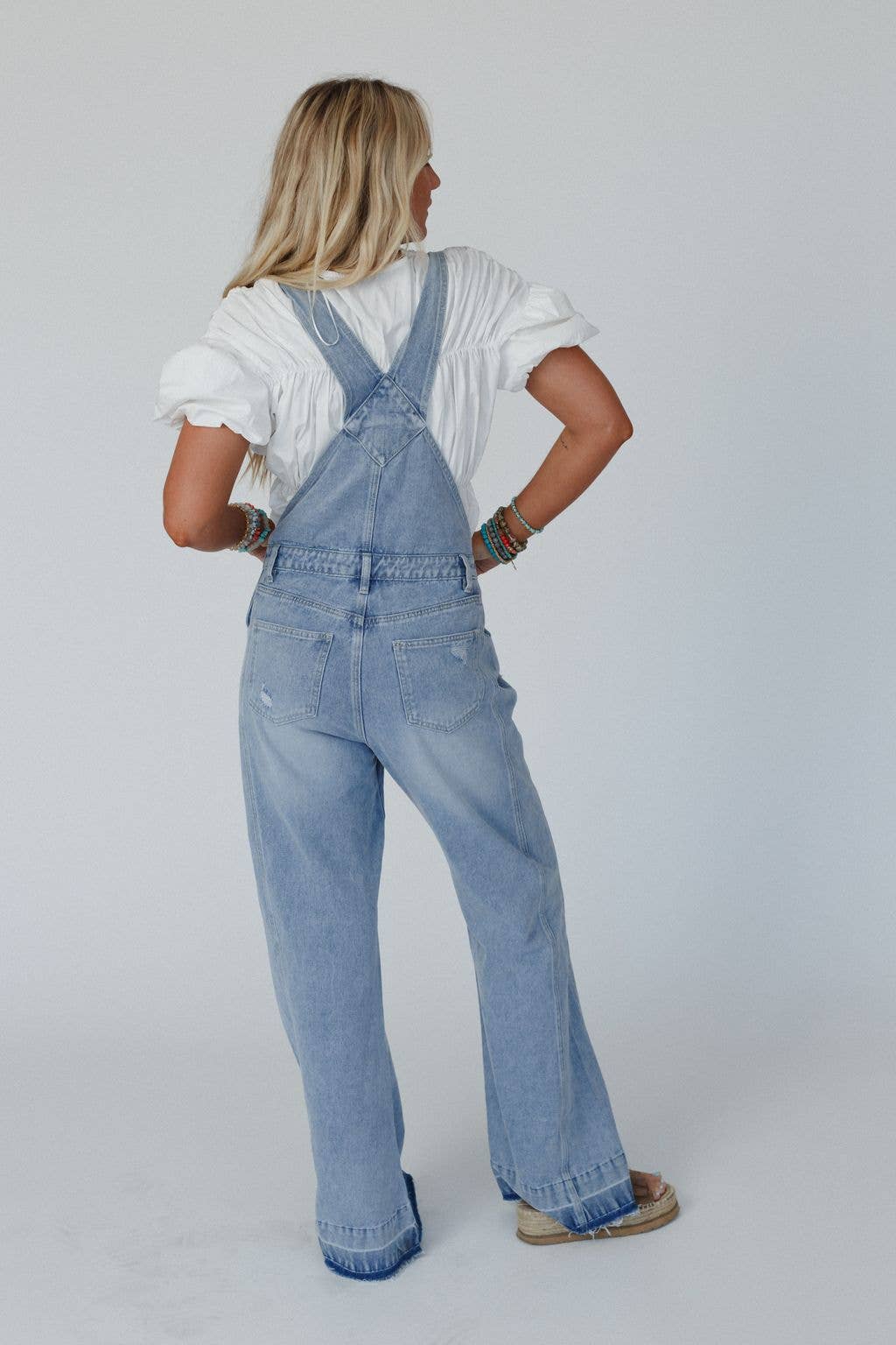 Back view of the Cali Dream Denim Overalls in light wash, showcasing the adjustable straps and functional back pockets.