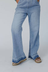 Detail of the double raw hem on the wide-leg Cali Dream Denim Overalls in light wash.
