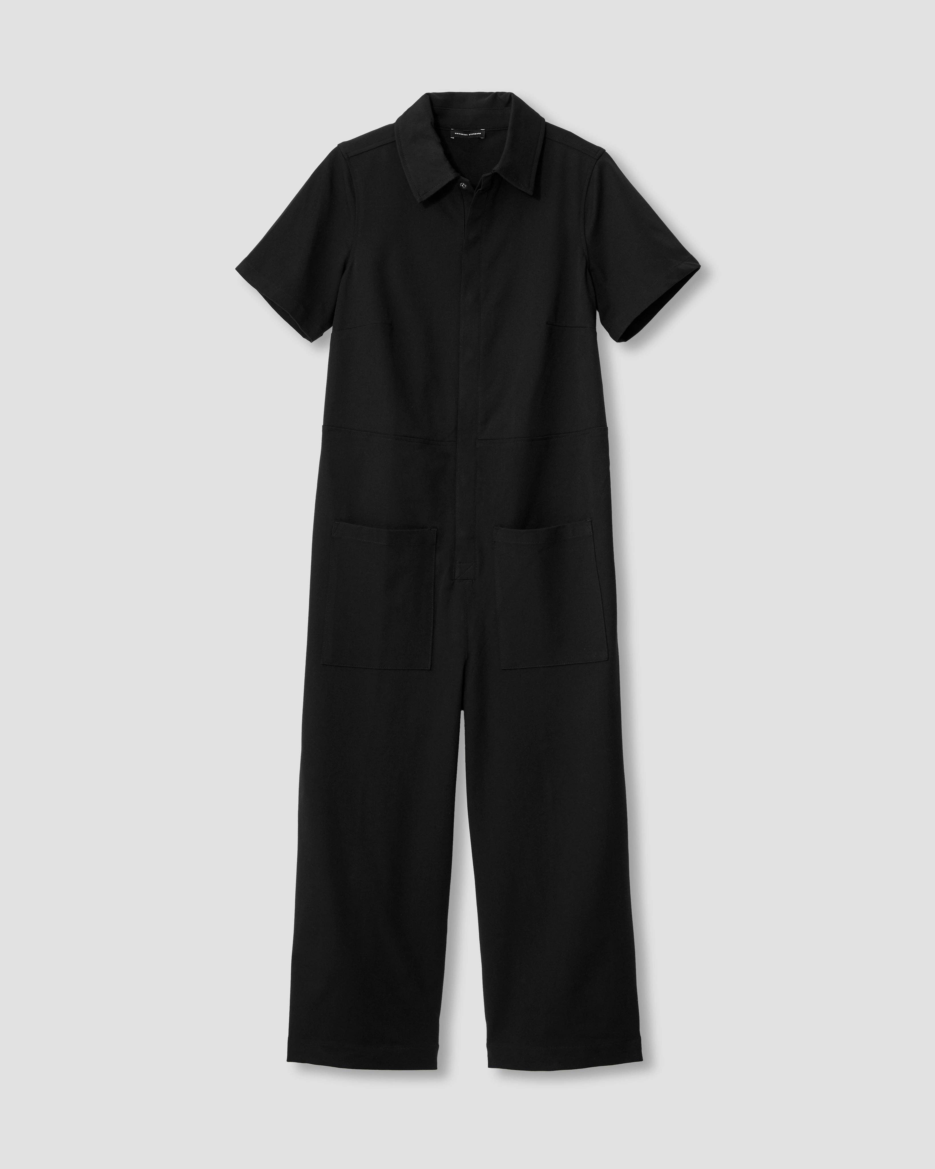Flat lay of the Kate Stretch Jumpsuit in black, showcasing its minimalist design and military-inspired style.