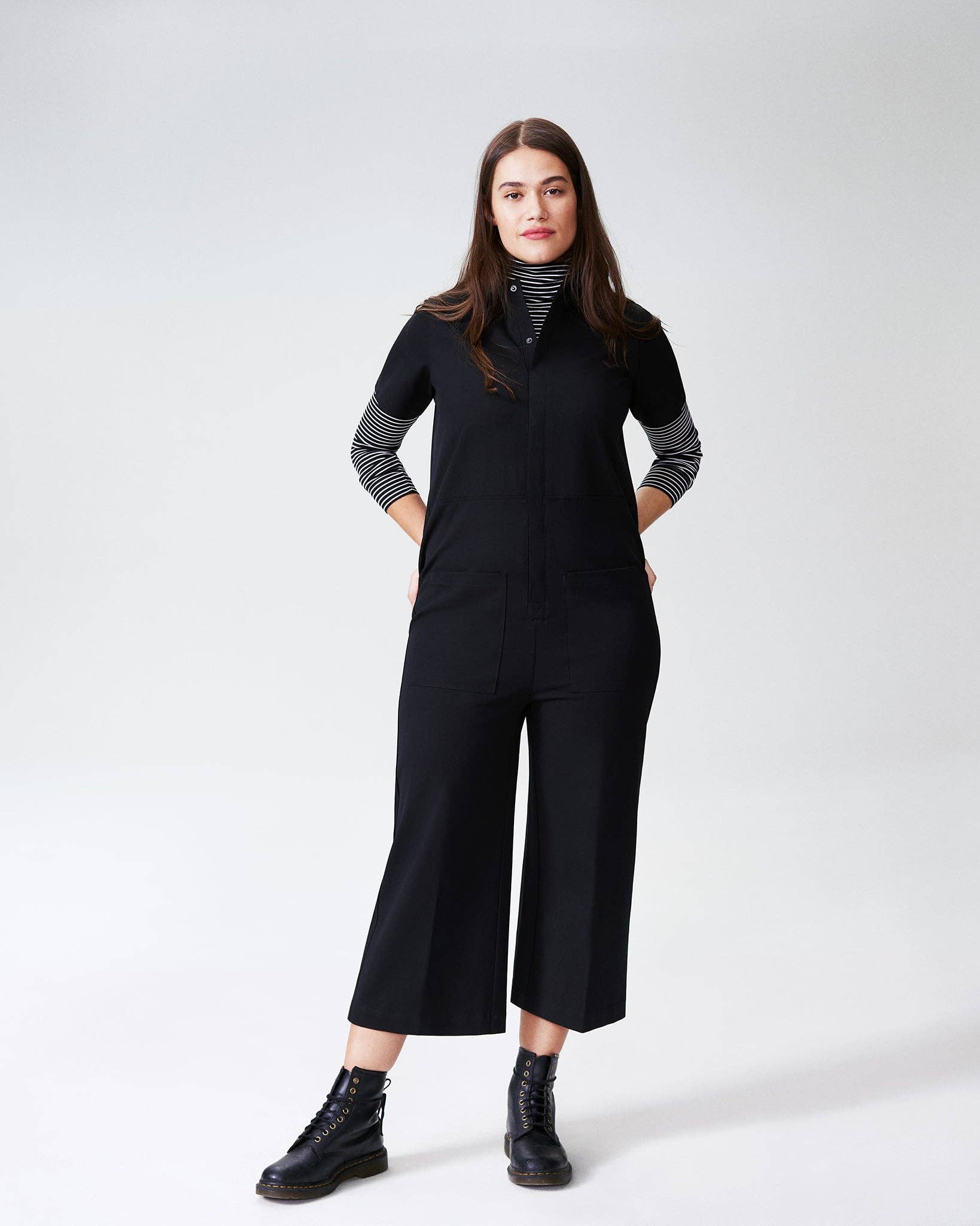 Model wearing the Kate Stretch Jumpsuit in black, styled with a striped turtleneck and combat boots for a casual look.