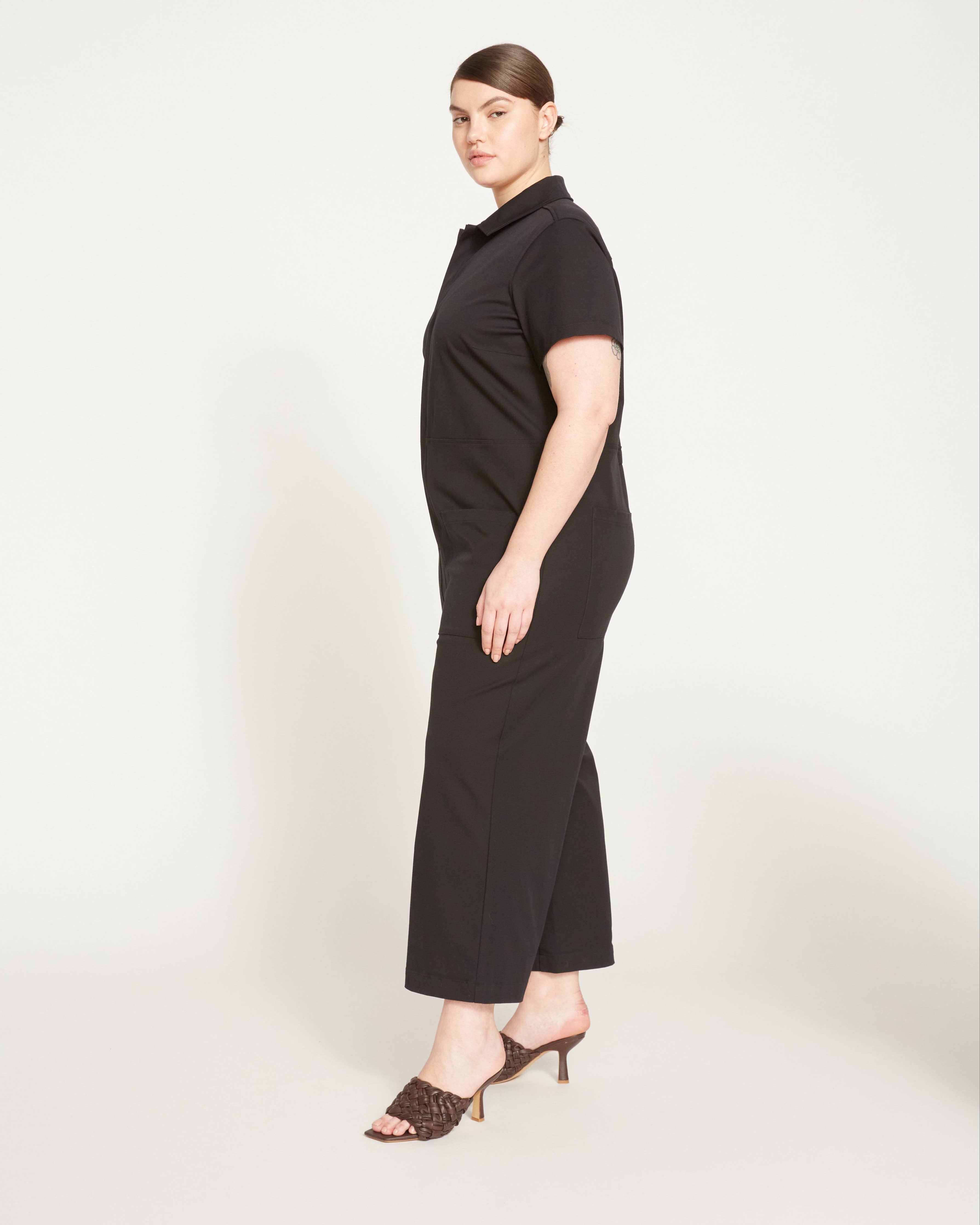Side view of the Kate Stretch Jumpsuit in black, featuring a relaxed fit and cropped legs for a modern silhouette.