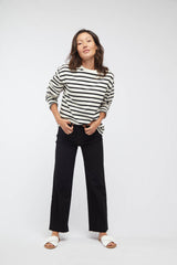 Woman wearing Aberdeen High-Rise Black Jeans by Oliver Logan, styled with a striped blouse and sandals, showing the cropped wide-leg fit and raw hem.