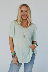 Front view of the THREE BIRD Nest Nestled tee in sage green, styled casually with light denim and layered beachy jewelry for an effortless boho look.