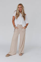 Full outfit view of Three Bird Nest Relaxing Robin Wide Leg Pant in New Taupe styled with a casual white top and layered bracelets.