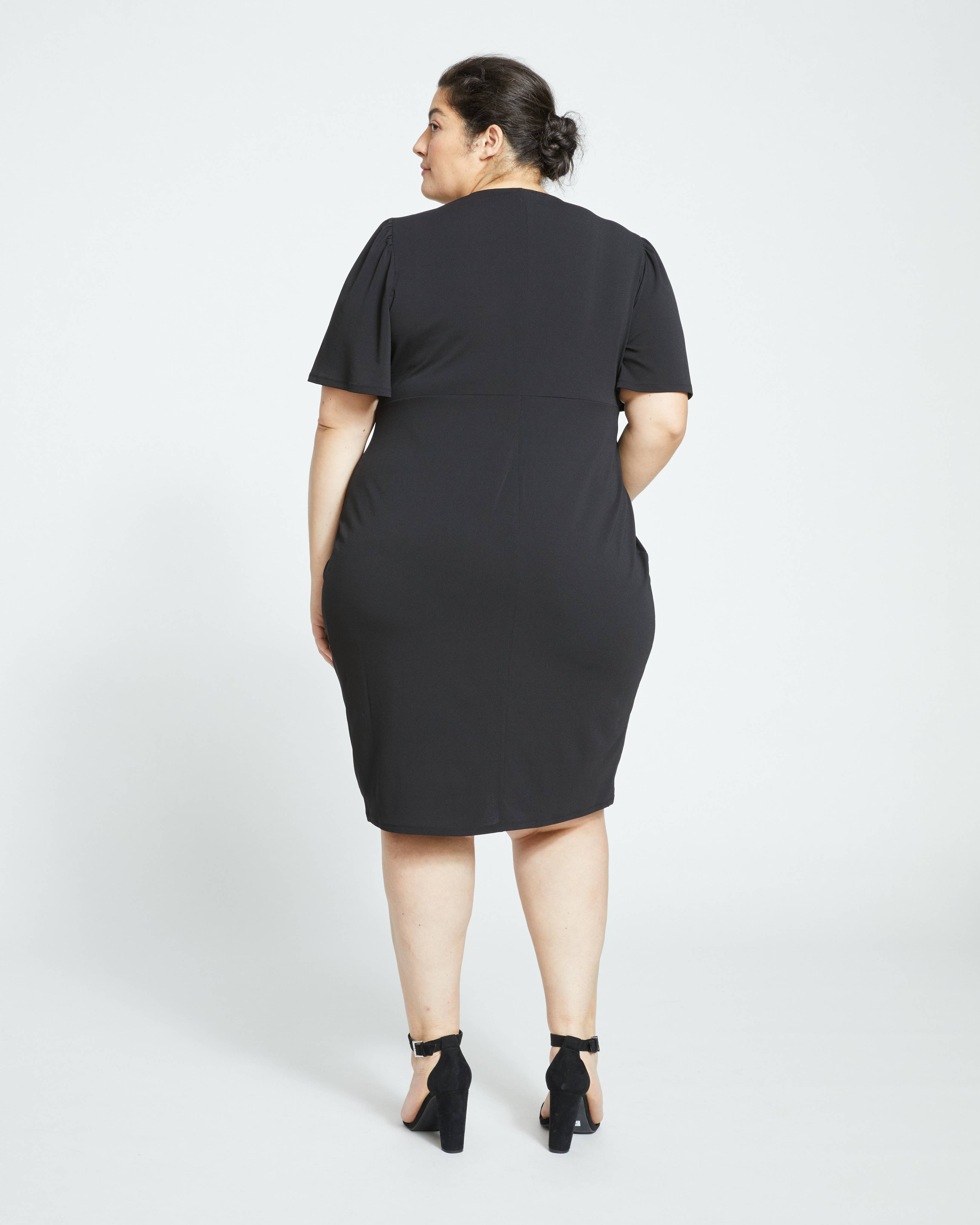 Back view of model wearing the Universal Standard Modiva Crepe Black Dress in Plus Size. 
